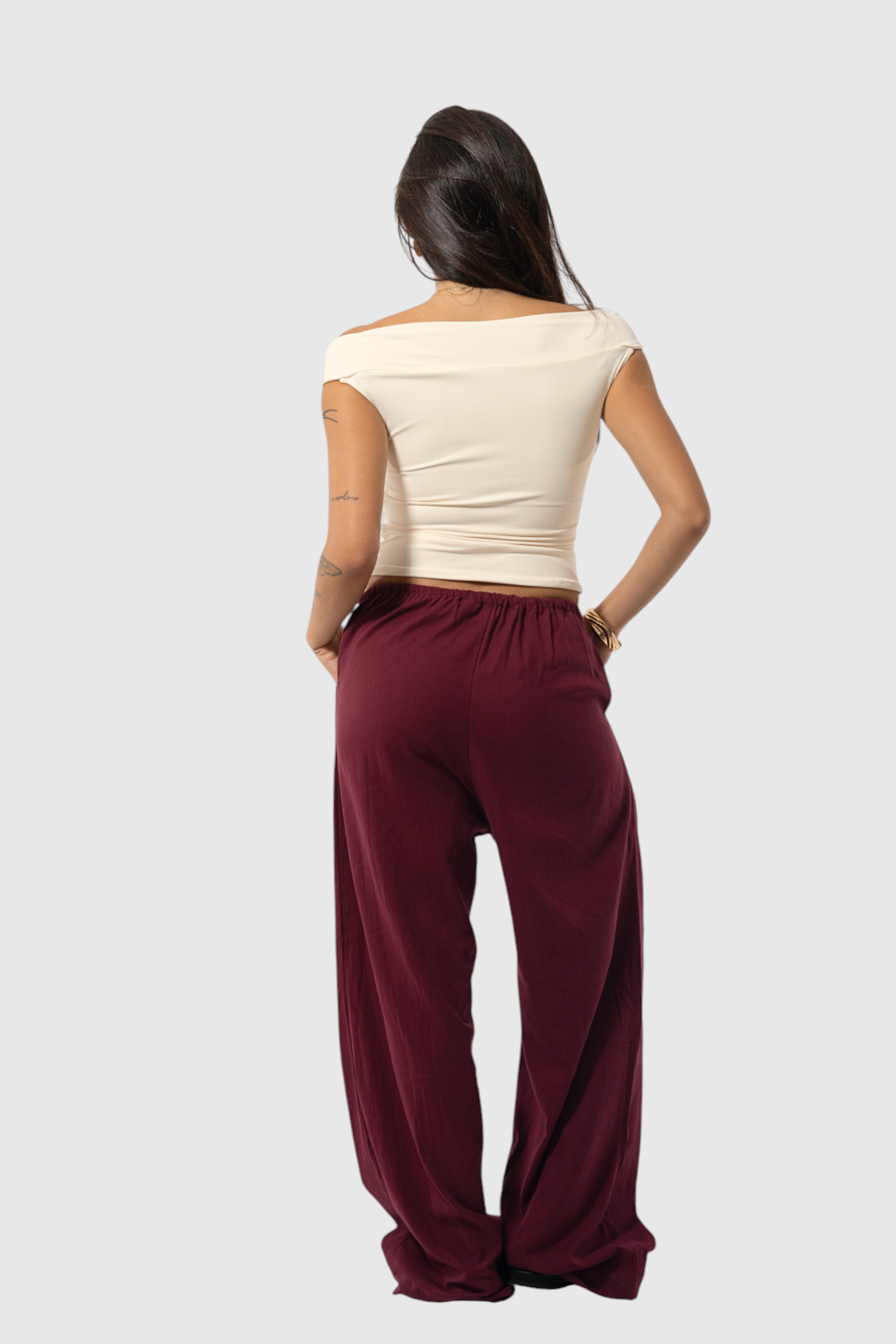 Modelo de costas usando calça básica de linho vinho com cintura regulável e corte amplo da LA MAGIE | Roupas Femininas