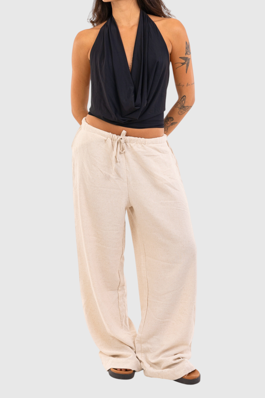 Modelo vestindo calça básica de linho bege com cordão ajustável na cintura da marca LA MAGIE | Roupas Femininas
