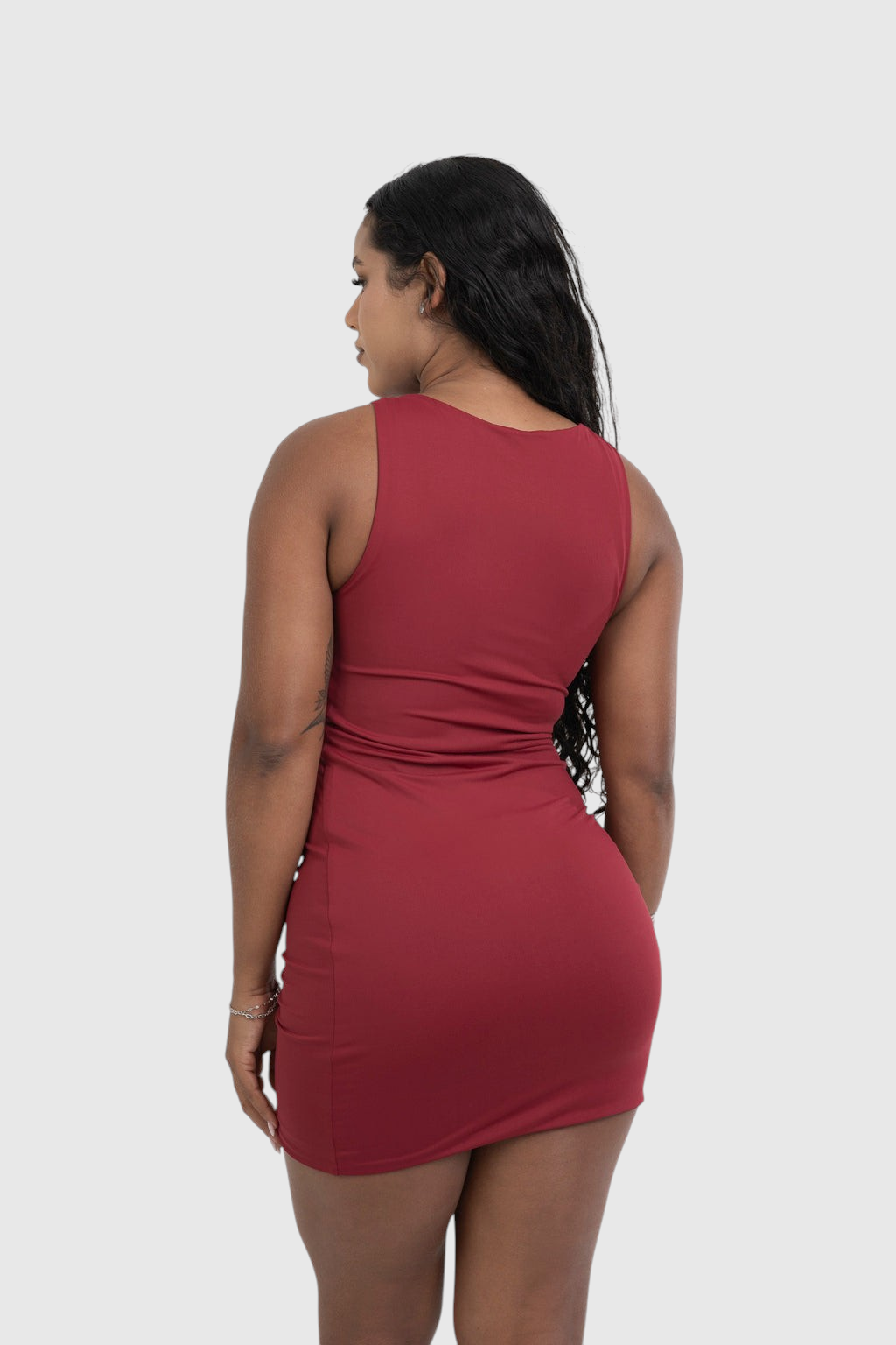Modelo de costas vestindo vestido curto vermelho LA MAGIE em malha de poliamida com decote canoa e caimento ajustado.