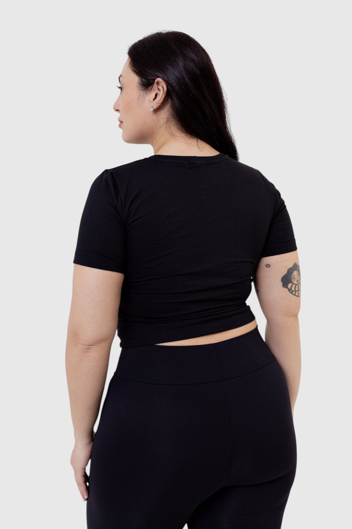 Modelo vestindo baby tee preta de algodão da LA MAGIE | Roupas Femininas Básicas e Estilosas, vista de costas.