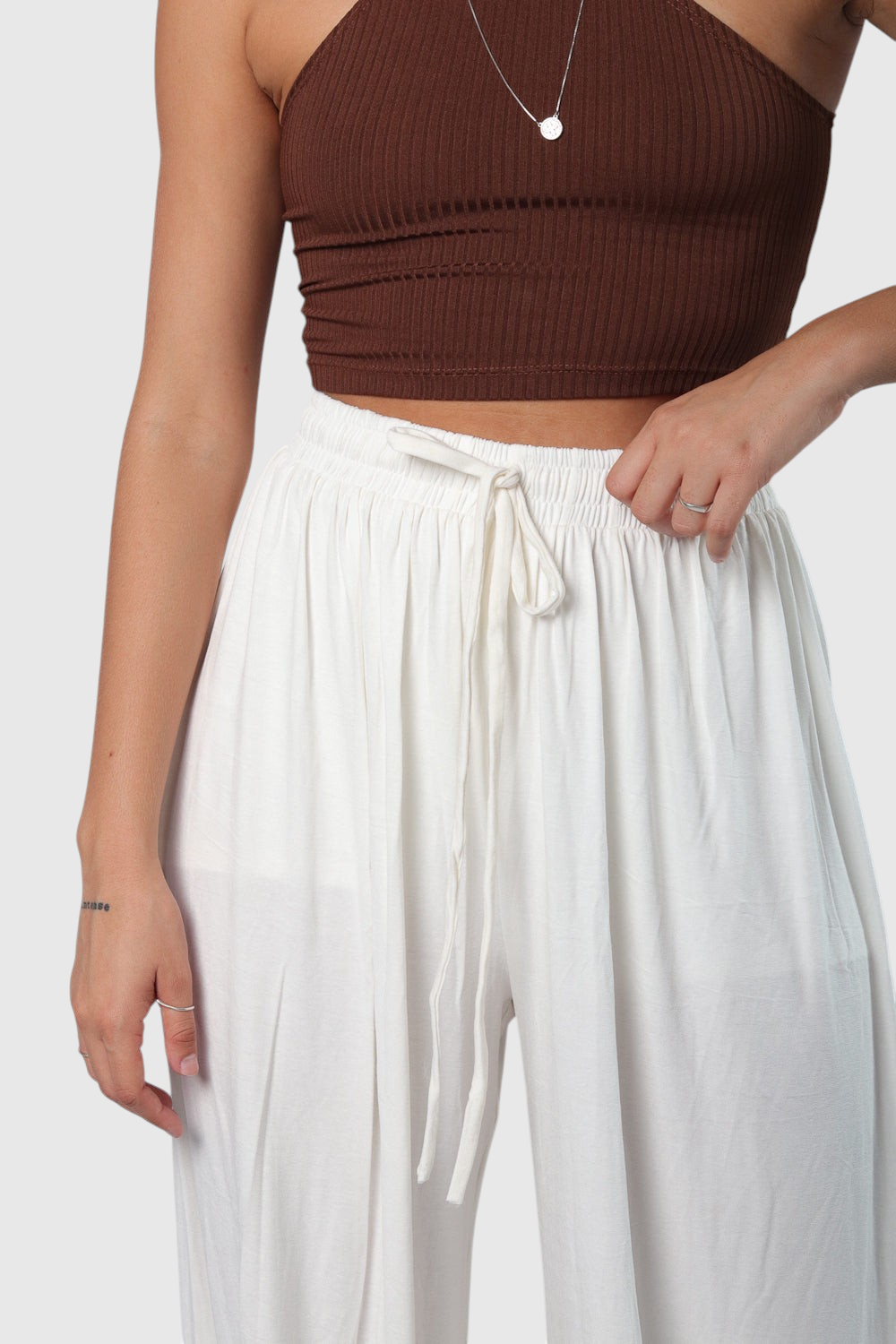 Pantalona off white LA MAGIE em viscolycra com cós de elástico e cordão regulável, modelagem ampla e confortável.