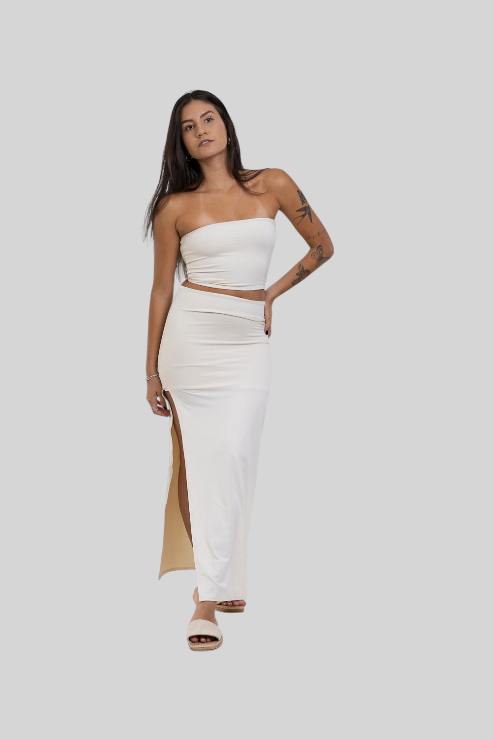 Modelo vestindo conjunto LA MAGIE com saia midi off-white de poliamida com fenda lateral e top tomara que caia