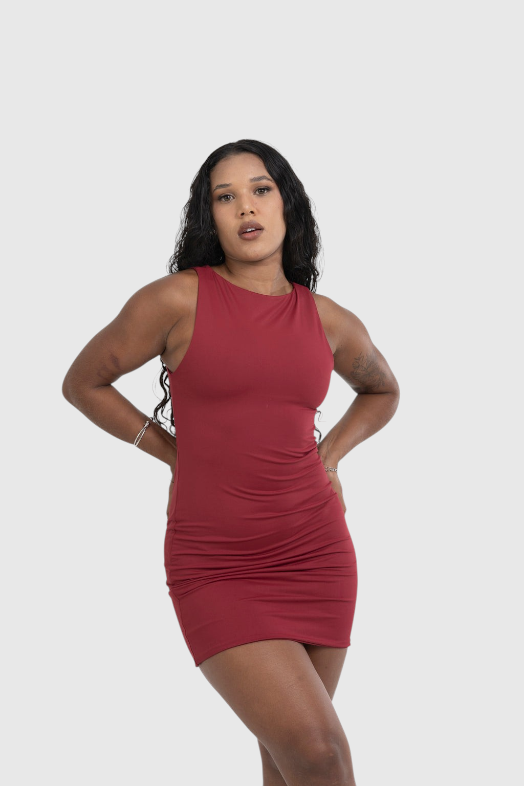 Modelo veste vestido curto vermelho LA MAGIE em poliamida com decote canoa e caimento ajustado ao corpo.
