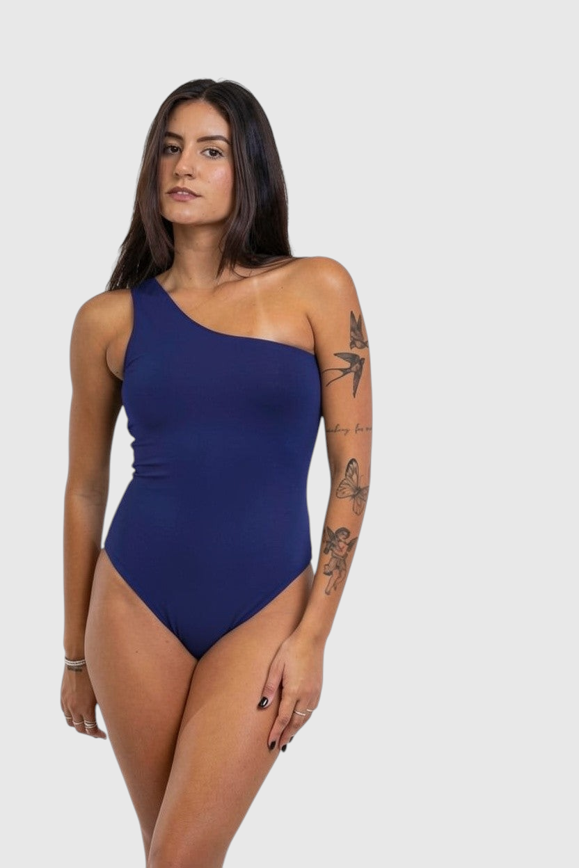 Modelo vestindo body azul marinho de um ombro só LA MAGIE | Roupas Femininas Básicas e Estilosas em poliamida macia.