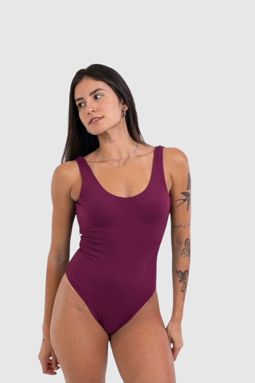 Modelo vestindo body cavado LA MAGIE na cor berry, com decote redondo e tecido de poliamida macio e flexível.