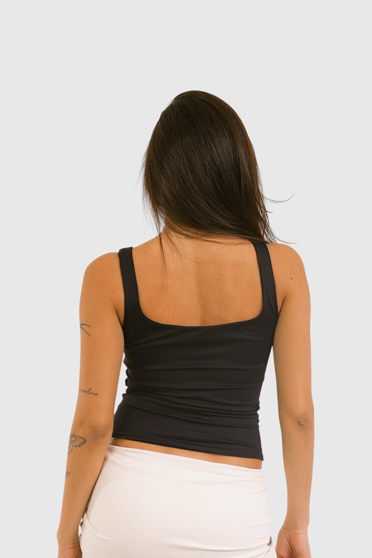 Modelo de costas vestindo blusa preta 2 em 1 LA MAGIE | Roupas Femininas Básicas e Estilosas em suplex de poliamida