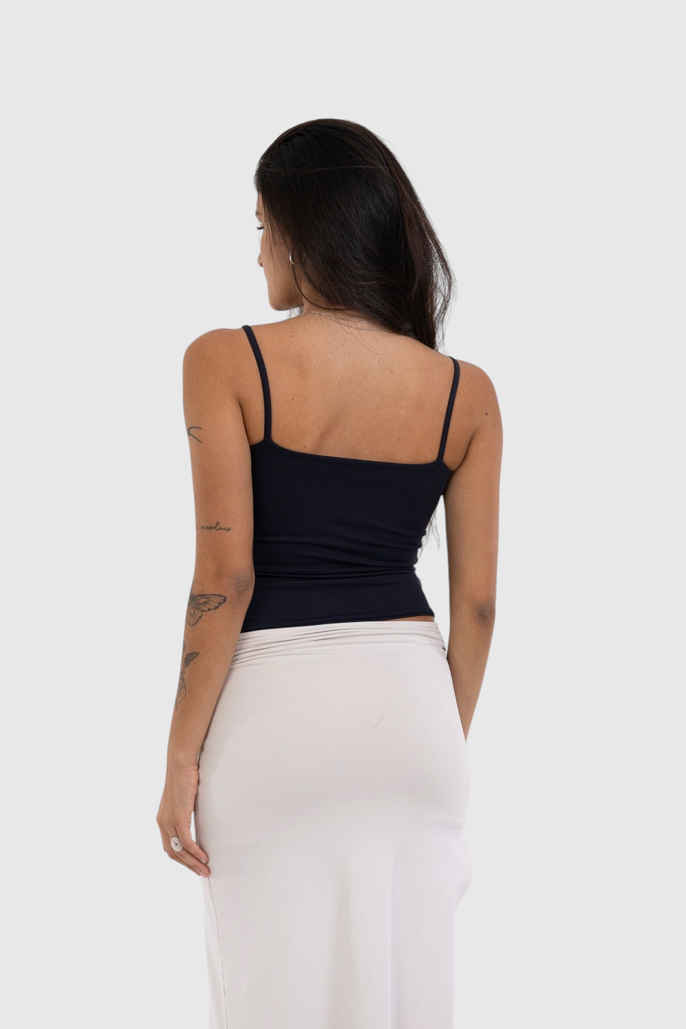 Modelo de costas vestindo blusa regata preta de alça fina em suplex de poliamida premium da LA MAGIE | Roupas Femininas Básicas e Estilosas