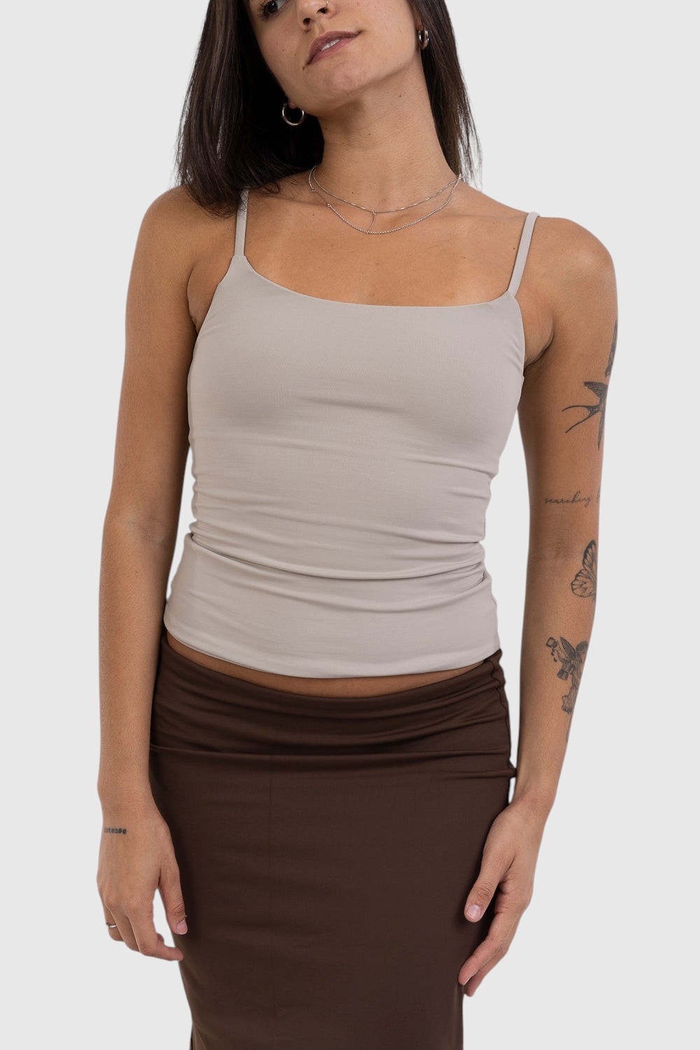 Modelo vestindo blusa regata bege de alça fina LA MAGIE em suplex de poliamida com ajuste segunda pele e forro duplo.