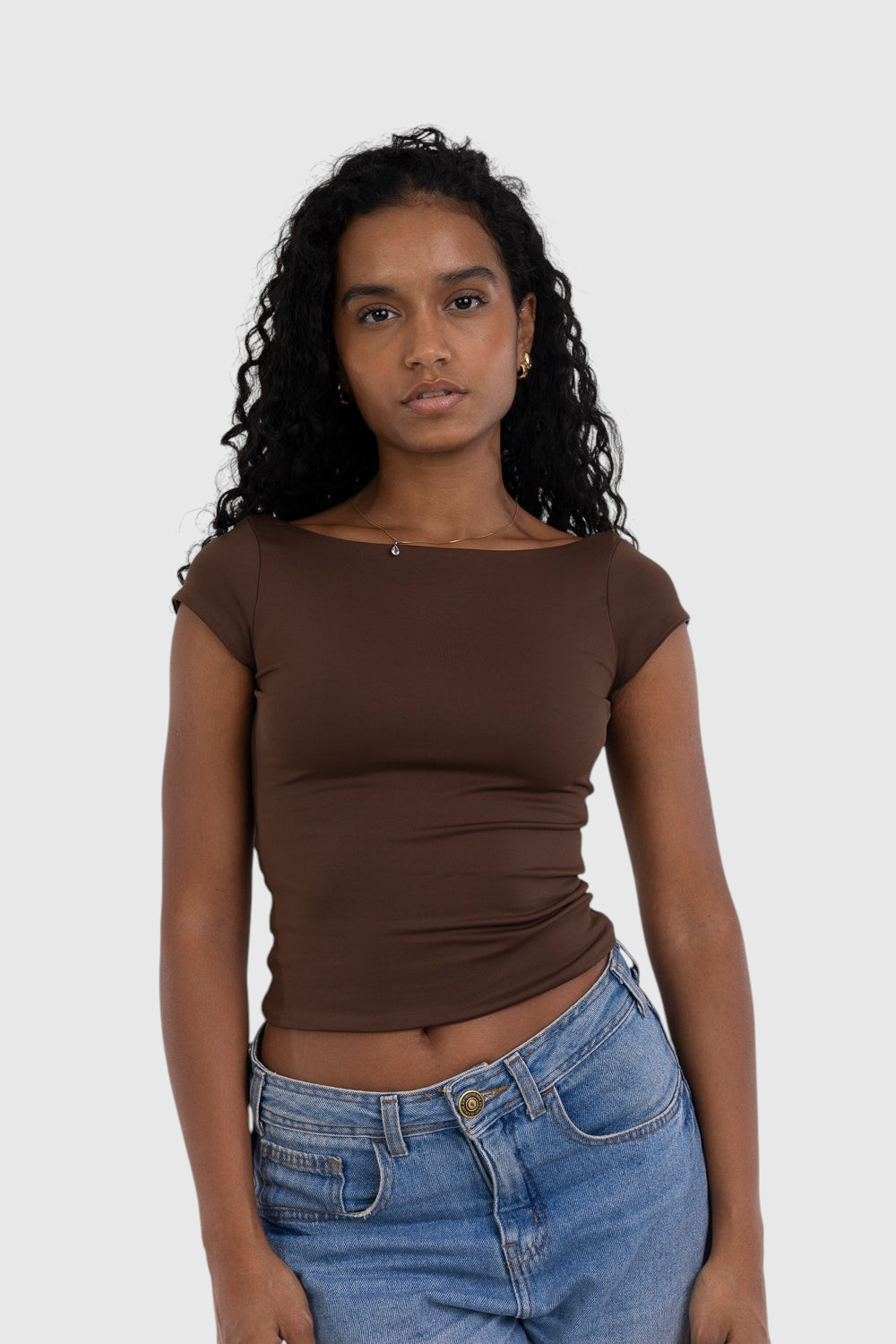 Modelo usando blusa marrom de manga curta LA MAGIE em suplex de poliamida com ajuste segunda pele e decote canoa.