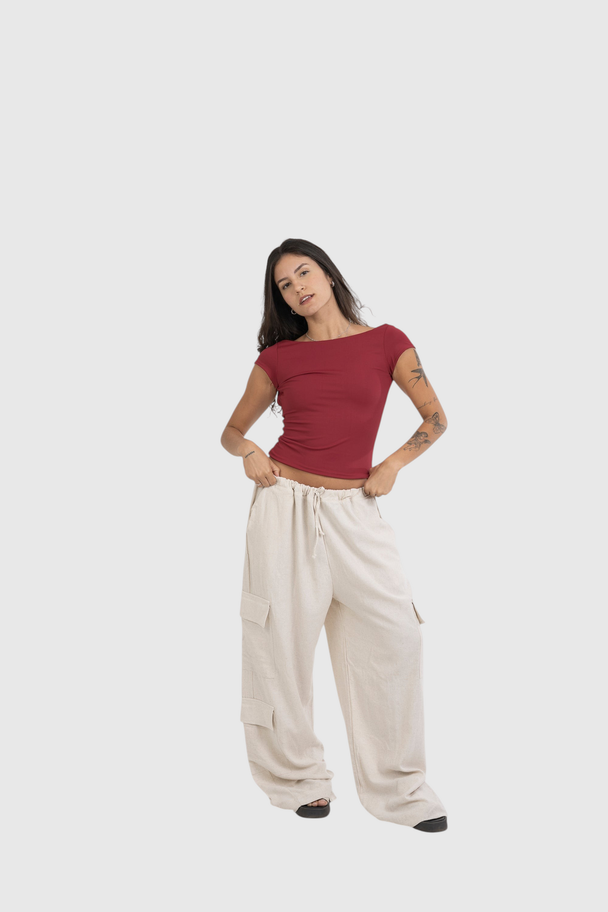 Modelo vestindo blusa vermelha de manga curta LA MAGIE com calça cargo bege em fundo neutro