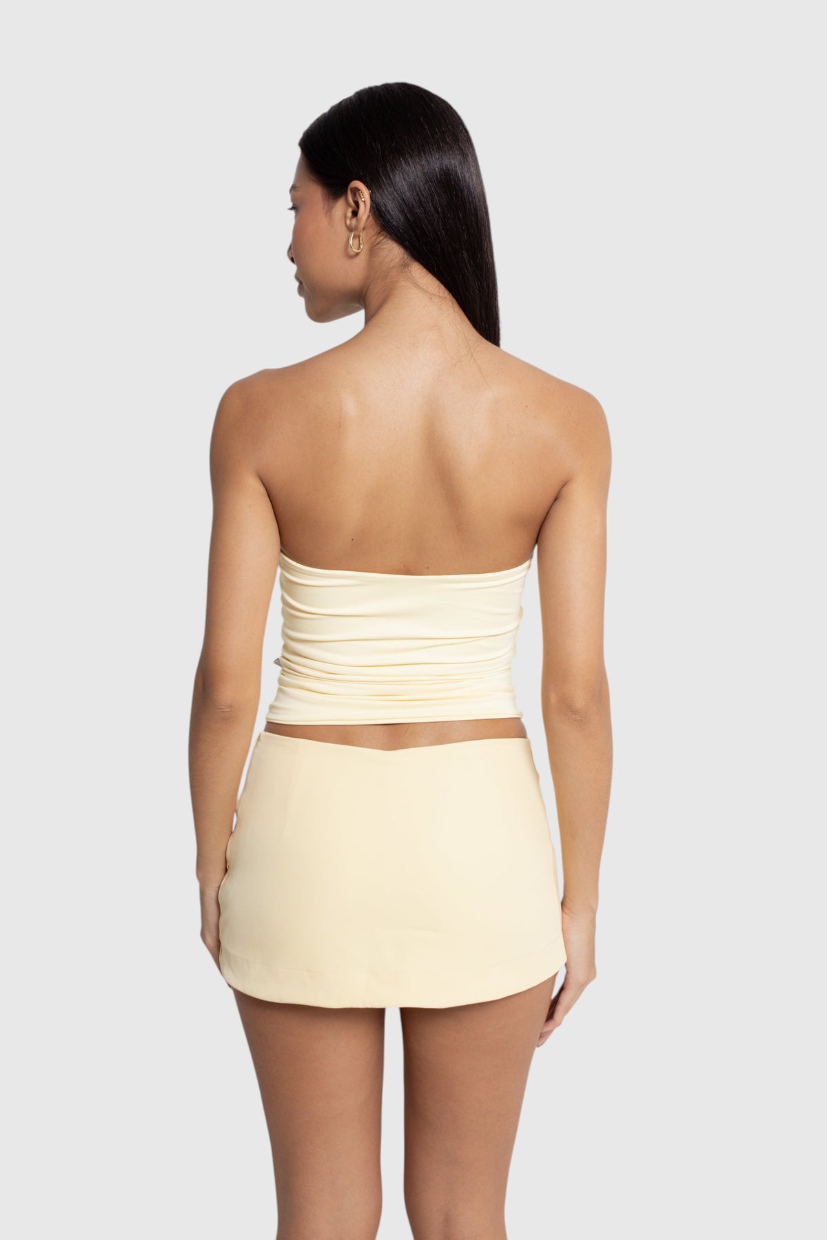 Modelo de costas vestindo blusa tube amarela LA MAGIE | Roupas Femininas Básicas e Estilosas em suplex de poliamida.
