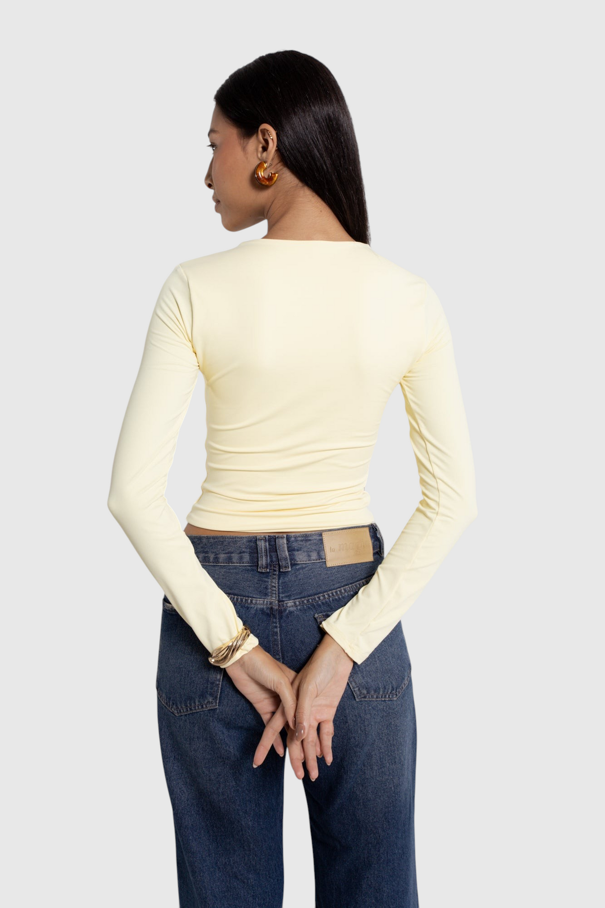 Modelo de costas vestindo blusa básica de manga longa amarela em poliamida da LA MAGIE | Roupas Femininas Básicas e Estilosas