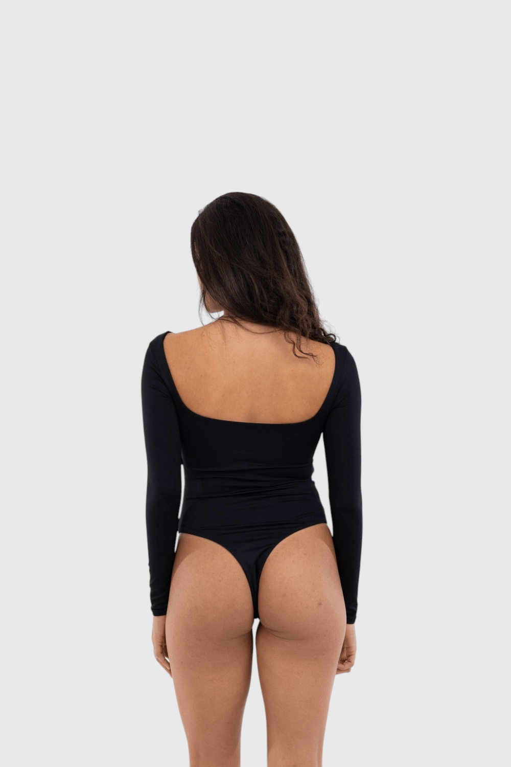 Modelo veste body LA MAGIE preto de manga longa com decote quadrado, feito em poliamida flexível e forro duplo.