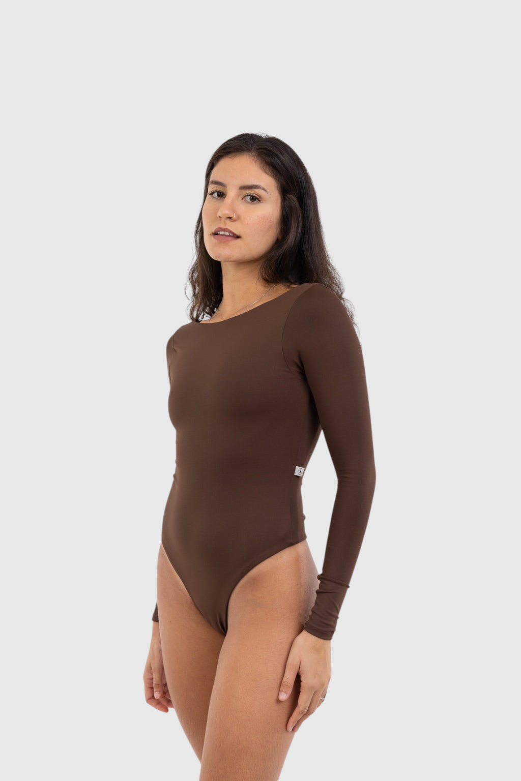 Modelo vestindo body marrom de manga longa LA MAGIE com decote versátil em poliamida de alta performance.
