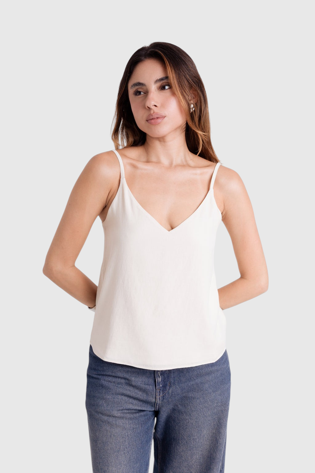 Modelo veste blusa LA MAGIE off-white de alça fina com decote em V em viscose rústica forrada e caimento soltinho.