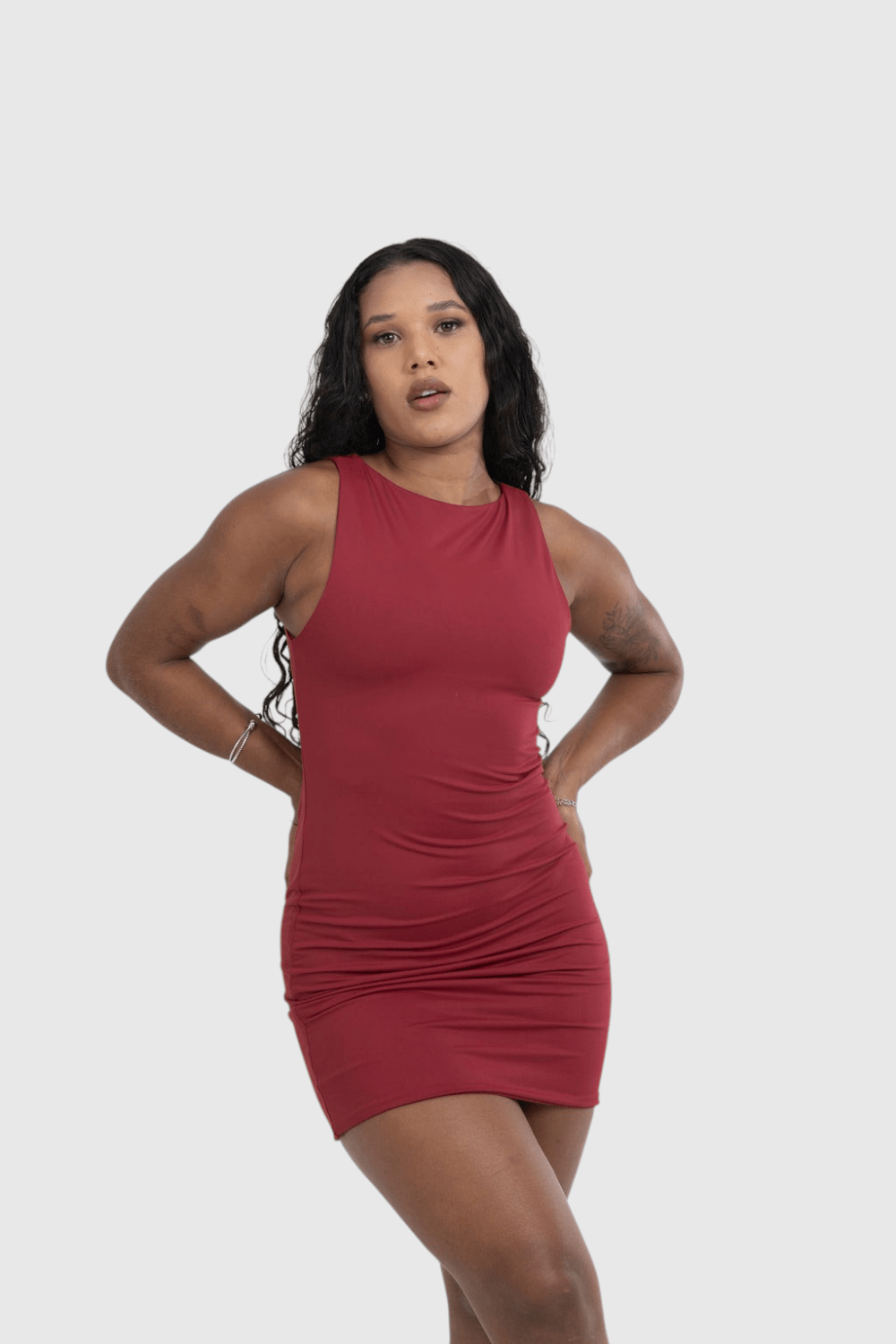 Modelo veste vestido curto vermelho LA MAGIE em poliamida com decote canoa e caimento ajustado ao corpo.